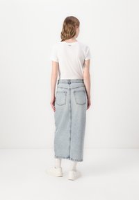 Lyseblå denimskjørt med høy midje, to baklommer og rett silhuett; sammen med en hvit t-skjorte med korte ermer og hvite sneakers.