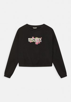 Sweat-shirt noir à manches longues avec col rond, ourlet élastique et logo "GUESS" blanc entouré d'une broderie florale rose et verte.