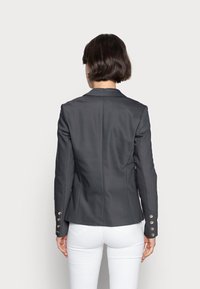 Grå skräddarsydd blazer i ett slätt tyg, med en enda bakventilation och guldknappsdetaljer på ärmarna.