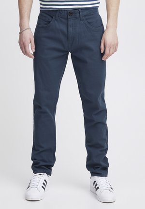 Marineblauwe katoenen broek met een klassieke pasvorm. Kenmerken zijn onder meer voorzakken, een knoopsluiting en stiksels. Gecombineerd met witte sneakers.