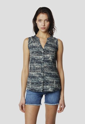 Camisa sin mangas con botones en un patrón abstracto azul y blanco, que presenta un escote en V, tejido texturizado y un ajuste relajado. Combinada con pantalones cortos de mezclilla.