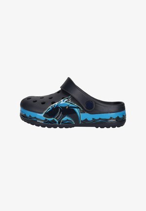 Sabot noir sans lacets avec des trous de ventilation et un motif de requin bleu sur le côté, contrastant avec des motifs de vagues bleues sur la semelle.
