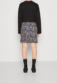 Felpa nera, gonna a fiori con accenti blu e stivali neri alti fino al ginocchio. Tessuto strutturato, vestibilità rilassata e design a più strati.