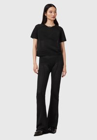 Zwart twee-delig outfit met een kortemouwen top en wijde broek, gemaakt van textuurstof met een ribbelstructuur en een subtiel verticaal patroon.
