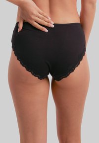 Black cotton briefs featuring a scalloped lace trim at the hem, smooth texture, and a fitted design that contours to the body.