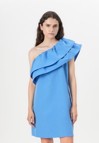 Robe bleue à une épaule en tissu lisse, avec un grand accent volanté autour de l'encolure, de longueur genou et une silhouette simple.