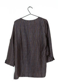 Blusa blu navy con scollo rotondo, maniche a tre quarti e un motivo a piccoli punti beige su uno sfondo a righe.