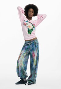 Roosa pika varrukaga särk lillelise trükiga, kombineeritud värviliste ja lahtiste teksadega, millel on värvipritsi mustrid ja hõbedane südamevöö.