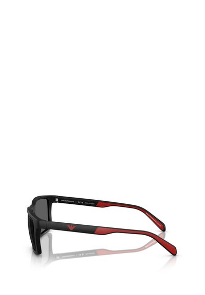 Des lunettes de soleil polarisées noires et rouges présentent une monture rectangulaire, une texture mate et des branches courbes avec un logo discret sur les côtés.