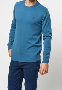 Sweter z dekoltem w łódkę w kolorze morskim, z długimi rękawami, ściągaczami przy mankietach i dole. Posiada małe logo na klatce piersiowej, wykonany z miękkiego dzianinowego materiału.