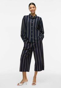 Camisa a rayas azul marino y culottes a juego, con un diseño de botones dorados, corte relajado y tejido ligero.