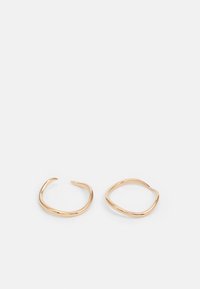 Orecchini a cerchio color oro con un design irregolare e ondulato. Un orecchino è leggermente arrotondato; l'altro è più ovale. Superficie liscia e lucida.
