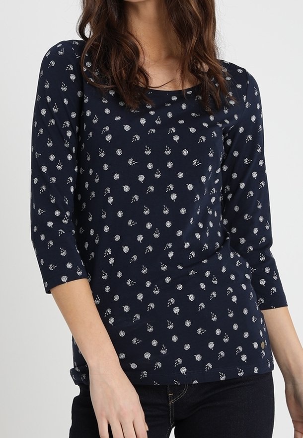 Tummansininen pitkähihainen paita, jossa on pyöreä pääntie. Paidassa on valkoinen kukkakuositus, pehmeä kangas ja sileä tekstuuri.