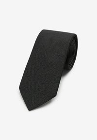 Corbata de etiqueta negra hecha de un tejido texturizado, con un extremo puntiagudo y forma enrollada, con un patrón sutil a lo largo.