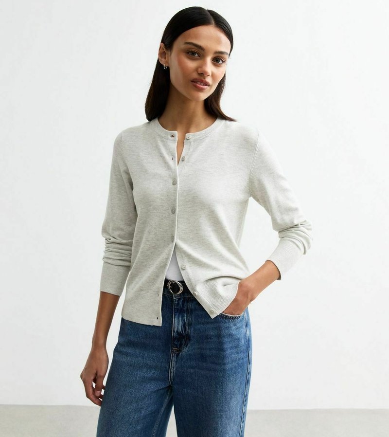 Ljusgrå cardigan gjort av mjukt stickat tyg, med rund halsringning, knappstängning och ribbade ärmar, i kombination med högmidjade blå jeans.