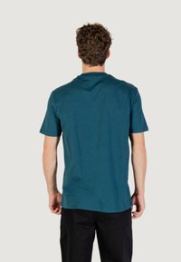 T-shirt en coton teal avec un col rond et des manches courtes, présentant une texture lisse et une coupe décontractée, vu de dos.