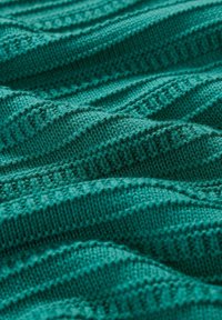 Teal knitted fabric with textured zigzag patterns and ribbed accents, showing a blend of tight and loose stitches in soft yarn.