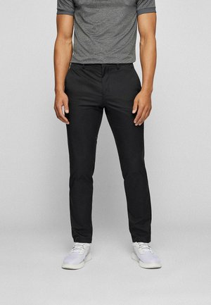 Zwarte chino's met een slim fit, gemaakt van een gladde stof. Gecombineerd met een grijs T-shirt met ronde hals en witte sneakers met veters.