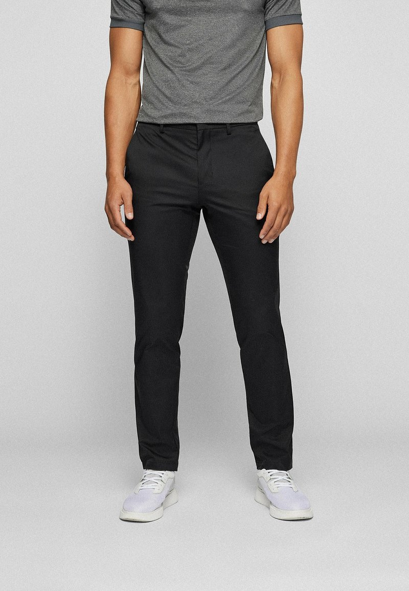 Chinos noirs à coupe slim, fabriqués à partir d'un tissu lisse. Associés à un t-shirt gris à col ras du cou et des baskets blanches, dotées d'un système de laçage.