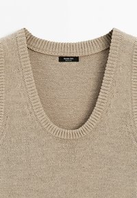 Beżowa dzianinowa kamizelka bez rękawów z prążkowanym okrągłym dekoltem i bocznymi panelami, markowa Massimo Dutti, wyprodukowana w Chinach.