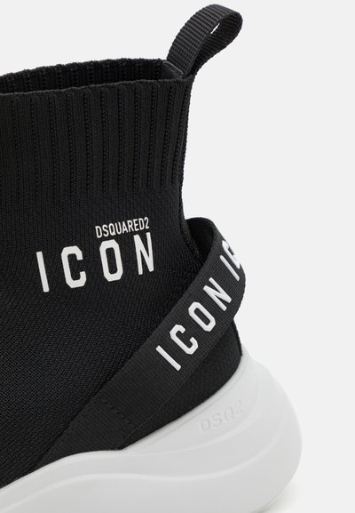 Crne pletene tenisice s rebrastim gornjim dijelom, bijelim tekstom "ICON" i kontrastnom bijelom potplatom; imaju petnu traku za lako obuvanje.