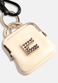 Pochette en cuir crème avec ferrures dorées brillantes. Présente un design en forme de lettre 'E' hexagonale ornée de clous à l'avant. Comprend une sangle noire.