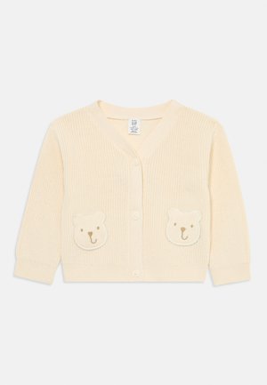 Kremfarget strikket baby cardigan med lange ermer, frontknapper og to bjørneansiktslapper nær midjen.