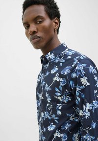 Camicia floreale blu navy realizzata in tessuto leggero, con design a bottoni e motivi di fiori blu e bianchi, e un colletto classico.