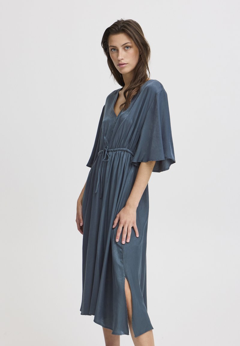Midikleid aus dunkelblauem Seidenstoff mit kurzen Ärmeln, V-Ausschnitt, verstellbarem Taillenzug und seitlichen Schlitzen für mehr Bewegungsfreiheit.