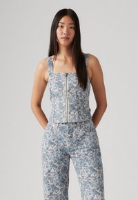 Top de denims com decote quadrado, fecho de zip e alças largas. Padrão floral azul claro com design ajustado. Combinado com calças florais a condizer.