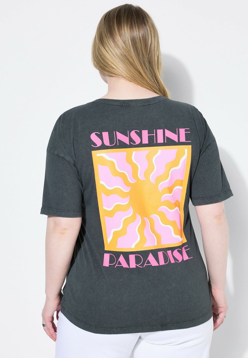 Camiseta gris oscuro de gran tamaño con un gráfico en la parte posterior que presenta un diseño de sol en amarillo y rosa. El texto debajo dice "PARAÍSO DEL SOL".