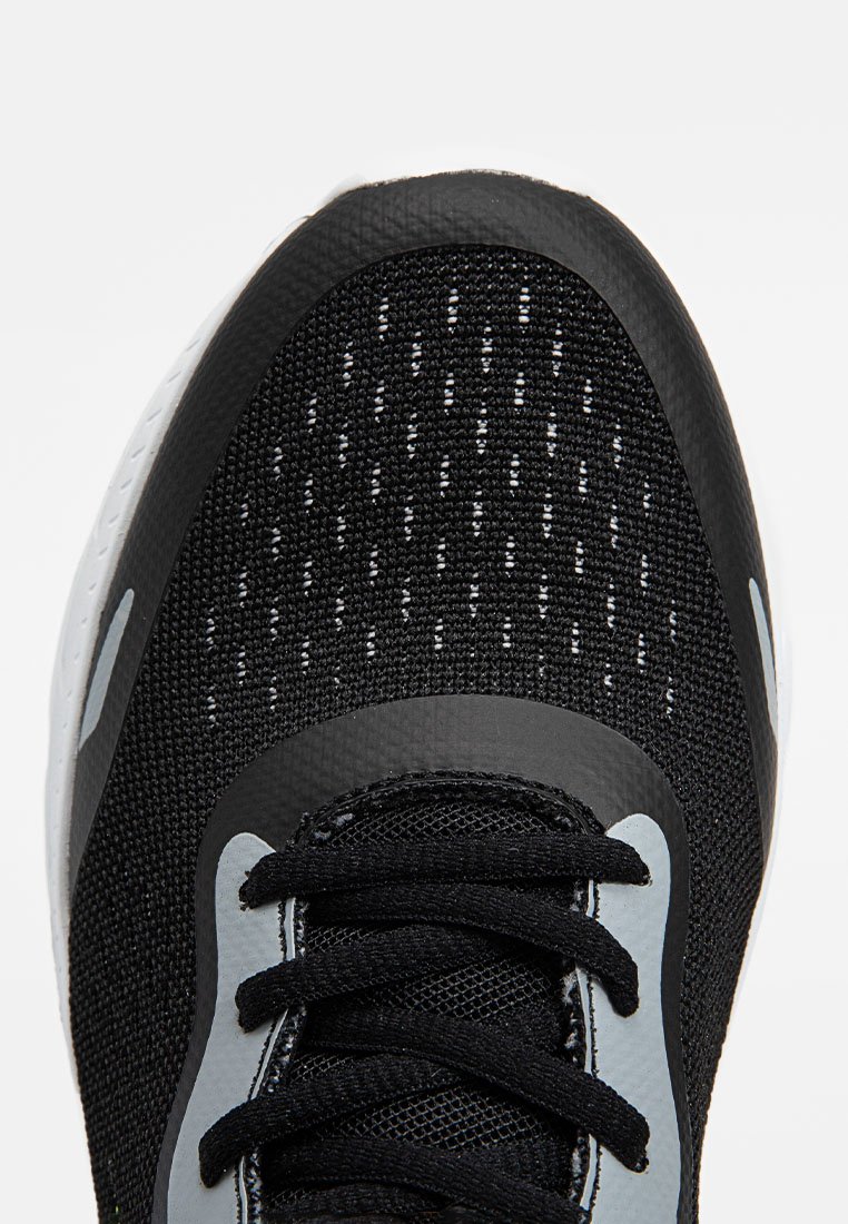 Vue de dessus d'une chaussure de sport noire, avec un dessus en maille texturée, des lacets noirs, des accents gris et une semelle blanche en caoutchouc.