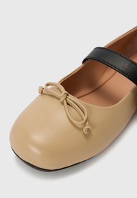 Beežni nahkbaletisaapad musta rihmaga ülevalt ja väikese kaunistuse sõrmenukil. Sile pind. Ümardatud varba kuju.