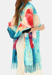Kolorowy szal z nadrukiem w odcieniach niebieskiego, czerwonego i pomarańczowego; lekka tkanina; wykończony frędzlami; narzucony na ramię.