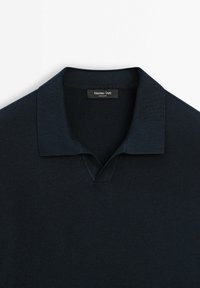 Merensininen poolopaita, jossa on pehmeä neulostekstuuri, klassinen kaulus, V-aukko ja merkkilappu kauluksen sisällä.