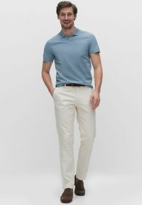 Ljusblå polo, vita byxor, bruna skor. Polon har krage och korta ärmar. Byxorna har rak benform. Enkelt, rent design.