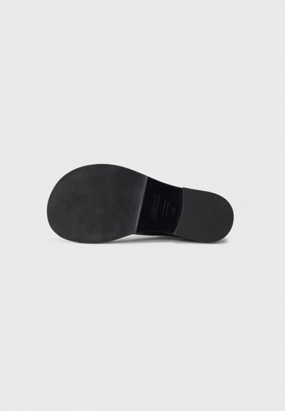 Black shoe sole with a smooth texture. Features a rounded shape, subtle tread pattern, and embossed logo details.