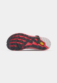 Trail running shoe outsole featuring a black and red rubber tread pattern, textured grips, and a yellow VIBRAM logo detail.