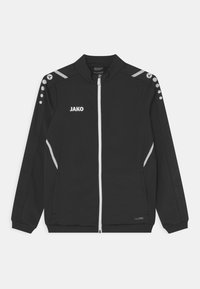 Zwarte sportjack met ritssluiting, zilveren accenten en een logo. Beschikt over schouderknopen en zijzakken. Gemaakt van gladde stof.