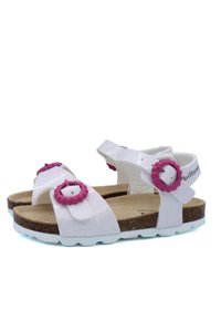 Sandales blanches avec des accents en forme de fleur rose, un matériau supérieur texturé, et une semelle en liège avec une semelle en caoutchouc blanche.