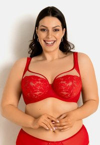 Czerwony koronkowy biustonosz z przezroczystymi panelami, kwiatowymi wzorami, fiszbinami podtrzymującymi i regulowanymi ramiączkami. Gładka tkanina na bazie z ozdobą z przodu.