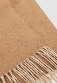 Fular din lână de culoare cămilă, cu un model în zigzag, finisat cu margini franjurate și un logo brodat subtil în crem.