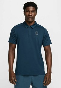 Marineblå polo skjorte laget av glatt, pustende stoff; har en to-knapps placket og en liten logo på venstre bryst.