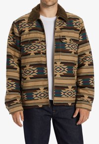 Brown patterned jacket with a tan background, featuring geometric designs in blue and dark brown. Fur-lined collar, two front pockets.
