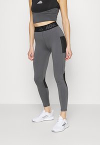 Leggings sportivi grigi con accenti neri, vita alta e design elegante. Realizzati in tessuto elastico per comfort e libertà di movimento.