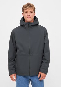 Donkere grijze waterdichte jacket met capuchon, voorzien van een frontale rits en elastische manchetten, gemaakt van soepel, lichtgewicht materiaal.