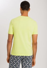 Lys gul kortærmet t-shirt med rund halsudskæring, parret med mønstrede blå og hvide shorts. Glat stof, afslappet pasform.
