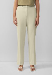 Beige, op maat gemaakte broek met een rechte pijp, voorzien van een scherpe voorkreuk, riemlussen en een soepele textuur. Gecombineerd met witte sandaaltjes met bandjes.