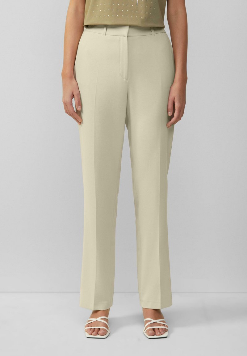 Beige, op maat gemaakte broek met een rechte pijp, voorzien van een scherpe voorkreuk, riemlussen en een soepele textuur. Gecombineerd met witte sandaaltjes met bandjes.