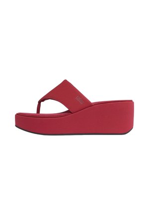 Red platform wedge sandal with a wide strap and toe post, featuring a black sole and branded detail on the strap.